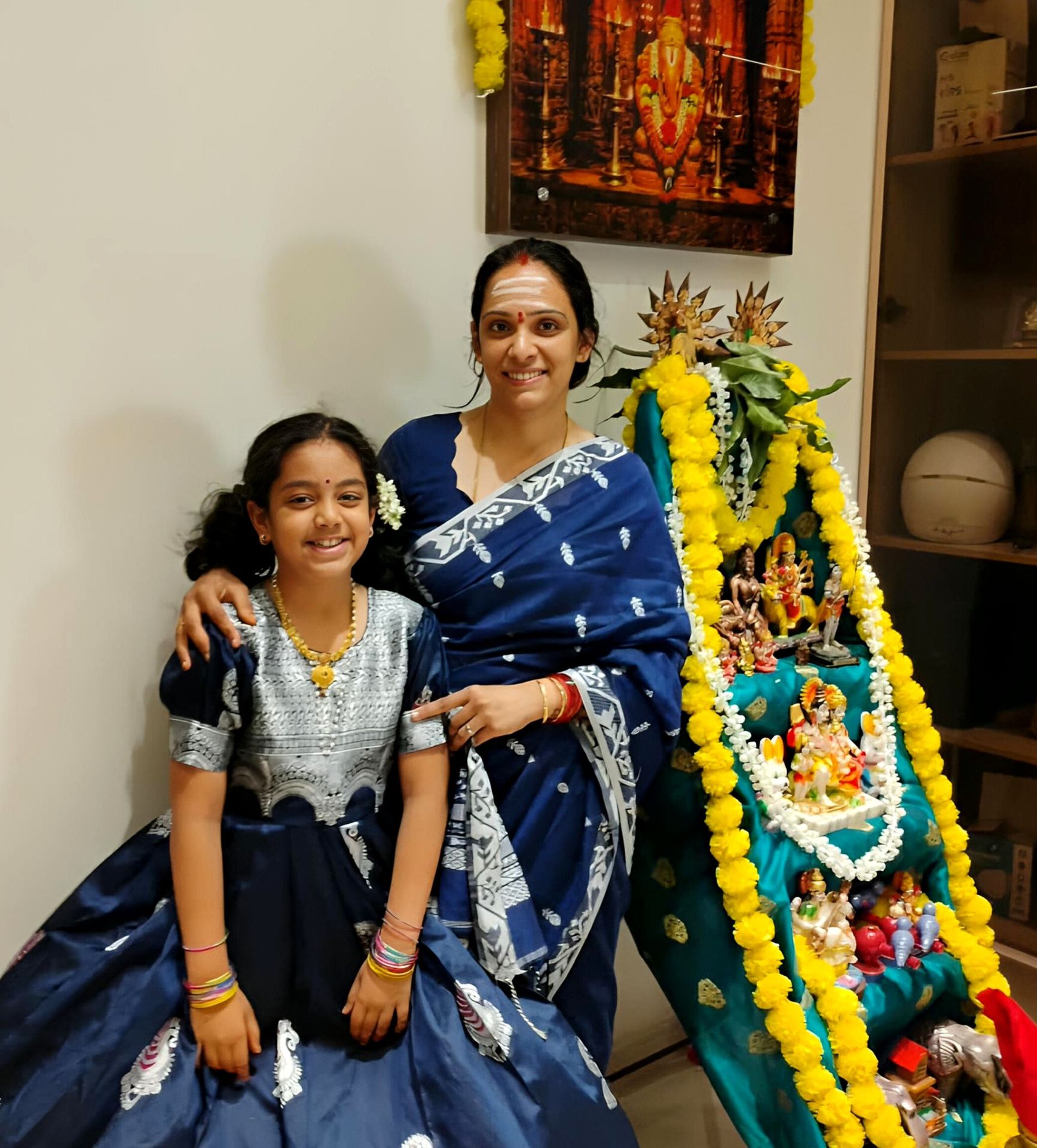 Mother and daughter standing beside their decorated Bommala Koluvu during Navratri. Our Bommala Koluvu Celebrations